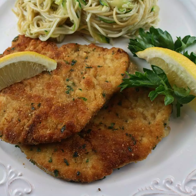 Golden-brown chicken cutlet served on a white plate