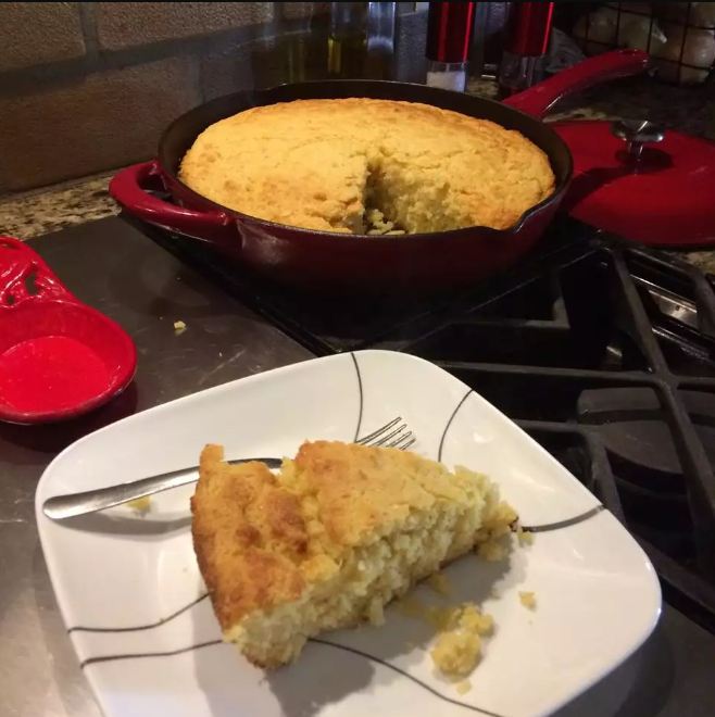 Golden Southern cornbread in a cast iron skillet on a rustic wooden table.