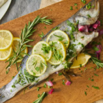 Grilled Branzino on a white plate garnished with lemon slices and fresh herbs