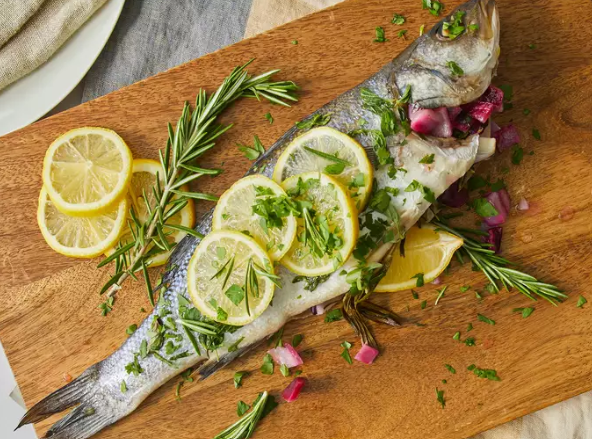 Grilled Branzino on a white plate garnished with lemon slices and fresh herbs