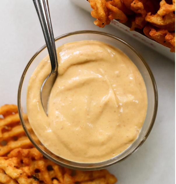 Bowl of homemade Chick-fil-A sauce with ingredients displayed around it, including mayonnaise, barbecue sauce, honey, and mustard.