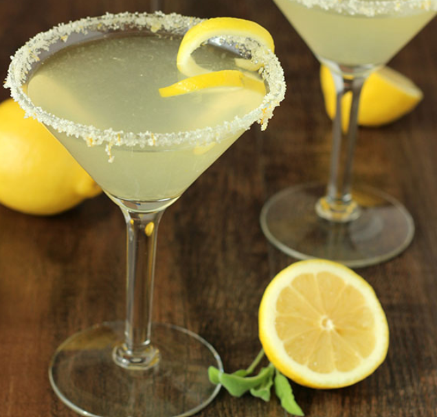 Preparation of a Lemon Drop cocktail showing lemon slices, vodka, triple sec, simple syrup, and a cocktail shaker.