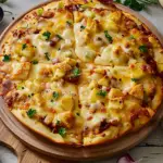 Delicious homemade BBQ Chicken Pizza topped with spicy barbecue sauce, tender chicken, red onions, pepperoncini peppers, cilantro, and melted Colby-Jack cheese.