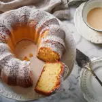 A moist Kentucky Butter Cake with a golden-brown crust, sliced to show its rich, buttery texture, topped with a light drizzle of vanilla butter sauce.