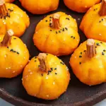 Festive no-bake Pumpkin Oreo Balls coated in orange candy melts with pretzel stems, perfect for fall parties.