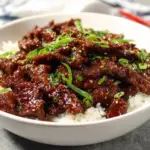 Alt text: A savory Mongolian beef recipe featuring tender beef strips coated in a rich, flavorful sauce, garnished with green onions and served with steamed white rice, all prepared in just 30 minutes.