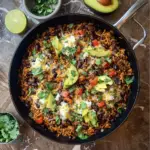 Alt text: "Colorful and hearty dish showcasing the Rice and bean skillet recipe, featuring a savory blend of fluffy rice, black beans, diced tomatoes, corn, and bell peppers garnished with fresh cilantro."
