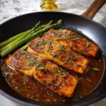 A delicious Honey Garlic Salmon Recipe featuring a perfectly cooked salmon fillet glazed with a rich, sticky honey garlic sauce, garnished with fresh herbs and lemon slices.