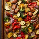 Alt text: A colorful Italian chicken sausage sheet pan dinner featuring roasted chicken sausages, bell peppers, zucchini, red onions, and cherry tomatoes beautifully arranged on a baking sheet seasoned with Italian herbs.