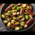 Alt text: "A vibrant dish featuring Honey Mustard Chicken Sausage with perfectly roasted Brussels Sprouts, garnished with fresh herbs and served on a rustic wooden platter."