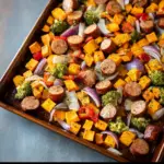 Alt text: "A colorful Cajun sausage and sweet potato recipe arranged on a sheet pan, featuring spicy sausage slices, vibrant sweet potato chunks, bell peppers, and onions, all seasoned with Cajun spices and baked to perfection."