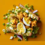 Alt text: A delicious crispy egg salad recipe featuring golden-fried egg halves atop a bed of fresh mixed greens, garnished with cherry tomatoes, red onions, and a sprinkle of herbs, served with a tangy vinaigrette.