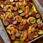 Alt text: "Colorful Cajun sausage and shrimp sheet pan recipe with sliced sausages, shrimp, bell peppers, and potatoes, seasoned with Cajun spices, baked to perfection on a sheet pan."